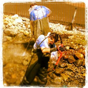 Two men cleaning a pond.